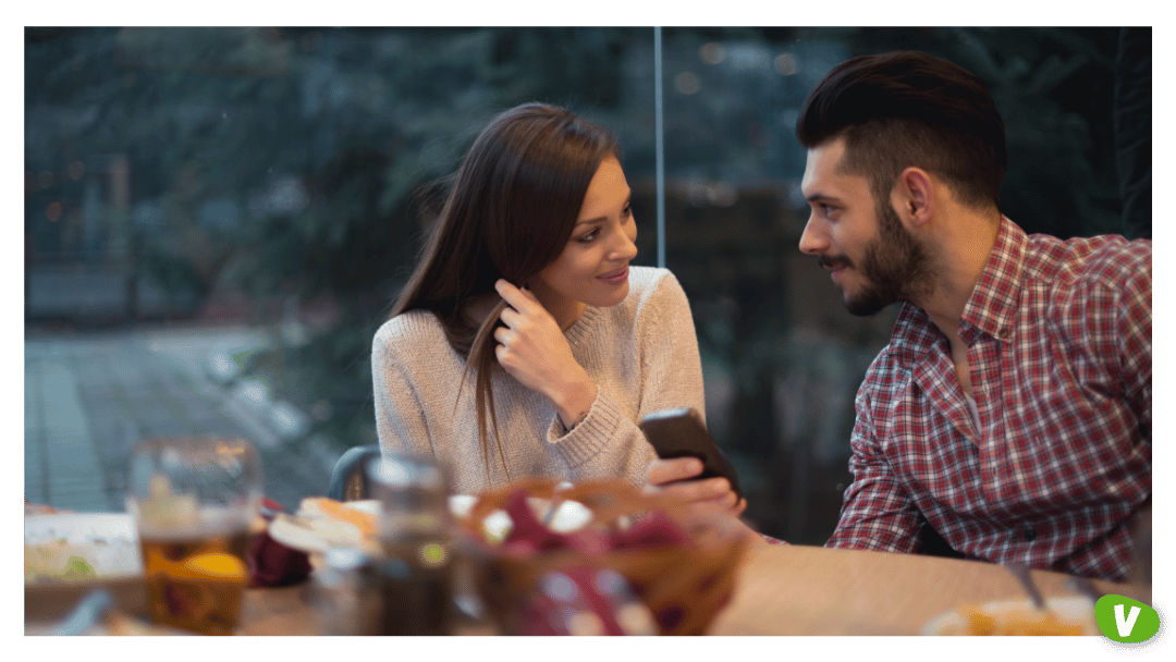 Couple dating woman showing something on her phone to her boyfriend