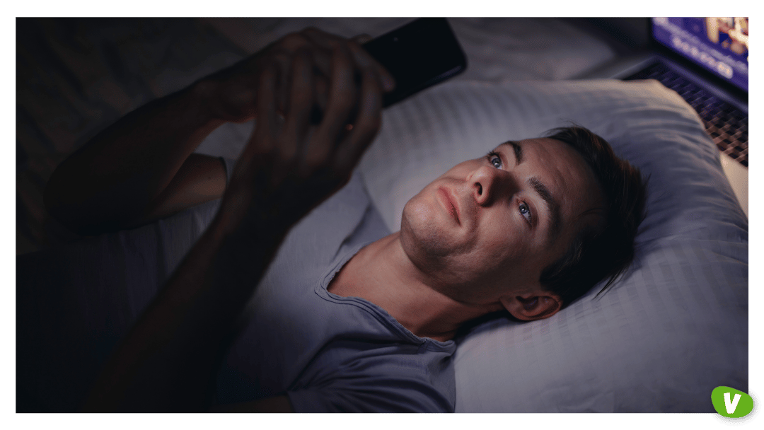 Man using phone in bed at night