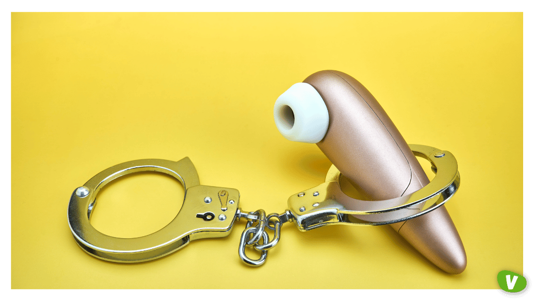 Closeup of a non-contact clitoris stimulator satisfyer and handcuffs on a yellow background