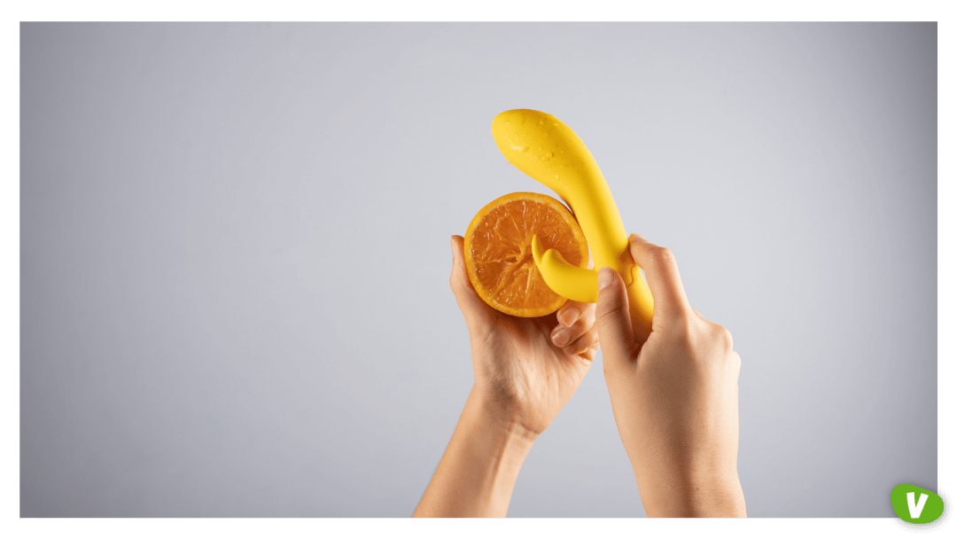 Female hand holding the sex toy and the orange